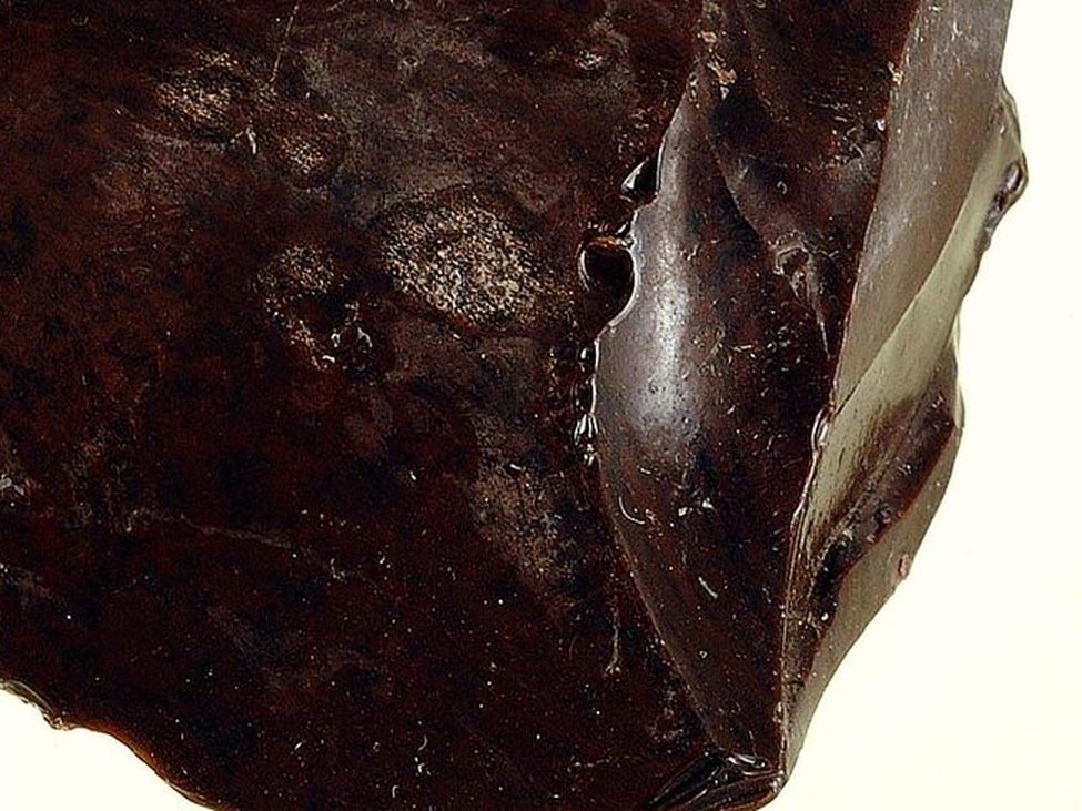 Raw obsidian showing its glassy conchoidal surface